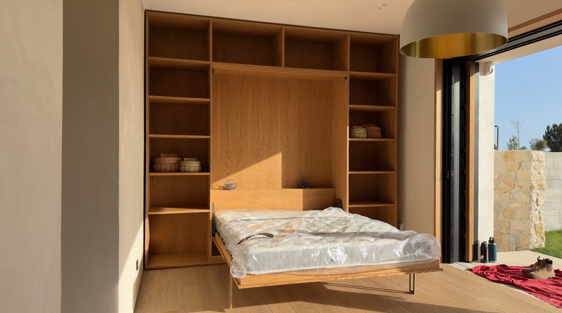 Oak murphy bed opened within fitted shelving wall