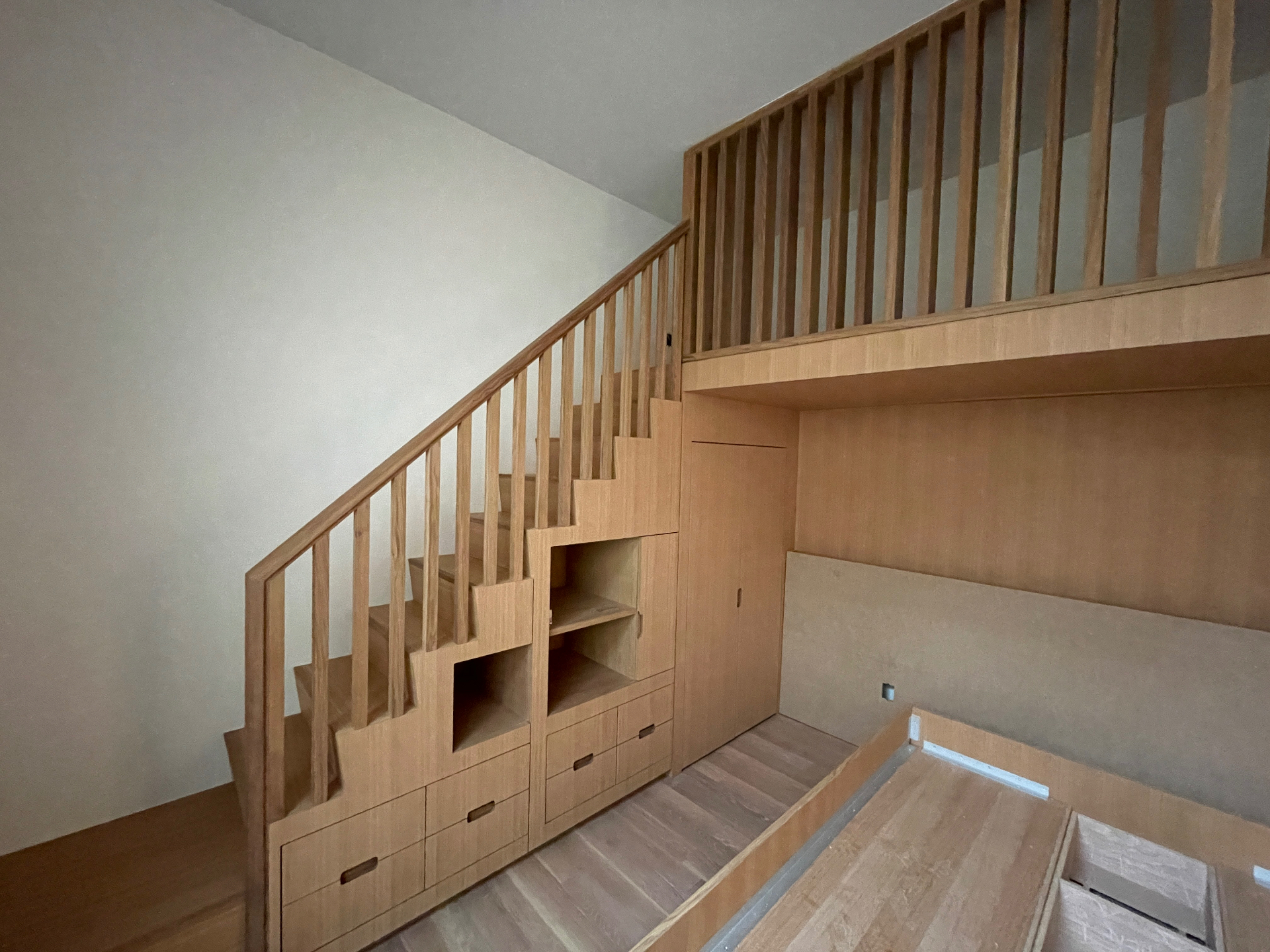 Oak staircase to the loft bed with integrated drawers and open cubbies