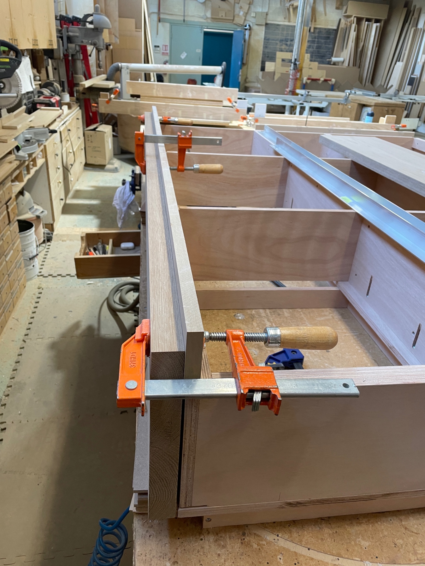 Long oak side rail clamped to the storage base during assembly