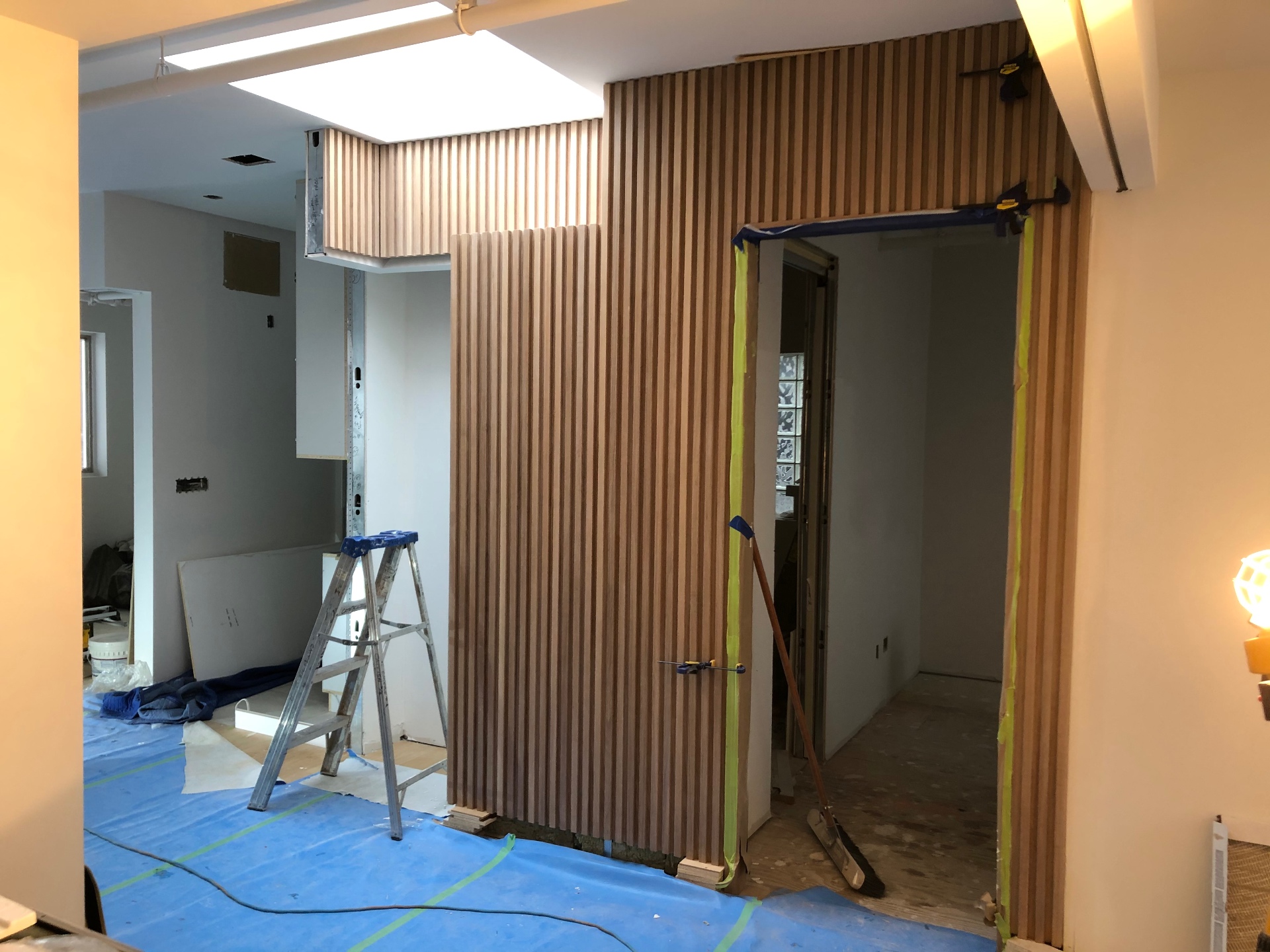 Floor-to-ceiling fluted oak wall wrapping a doorway in the same office