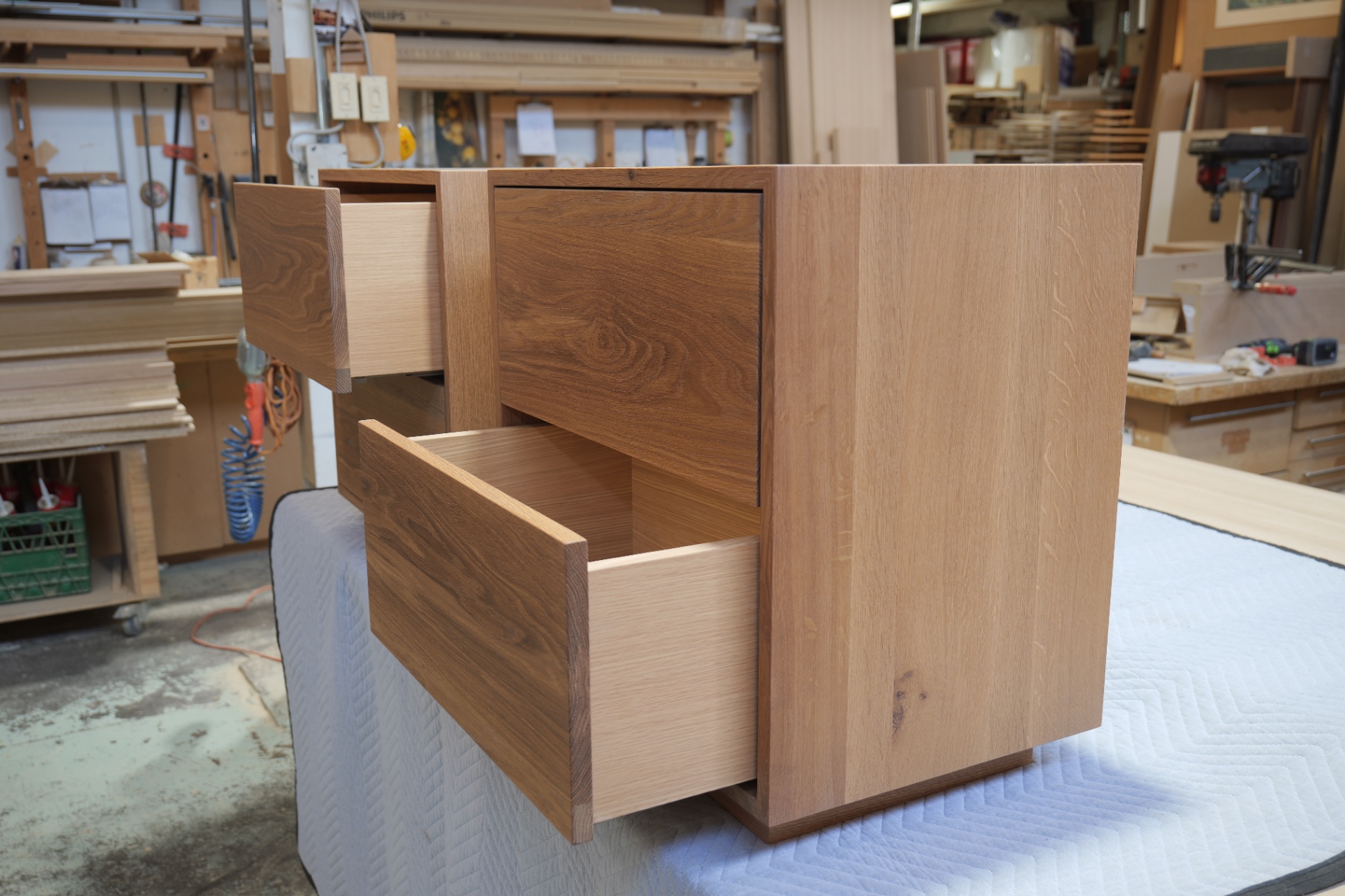 Angled view of the nightstand with drawers open showing the solid oak sides