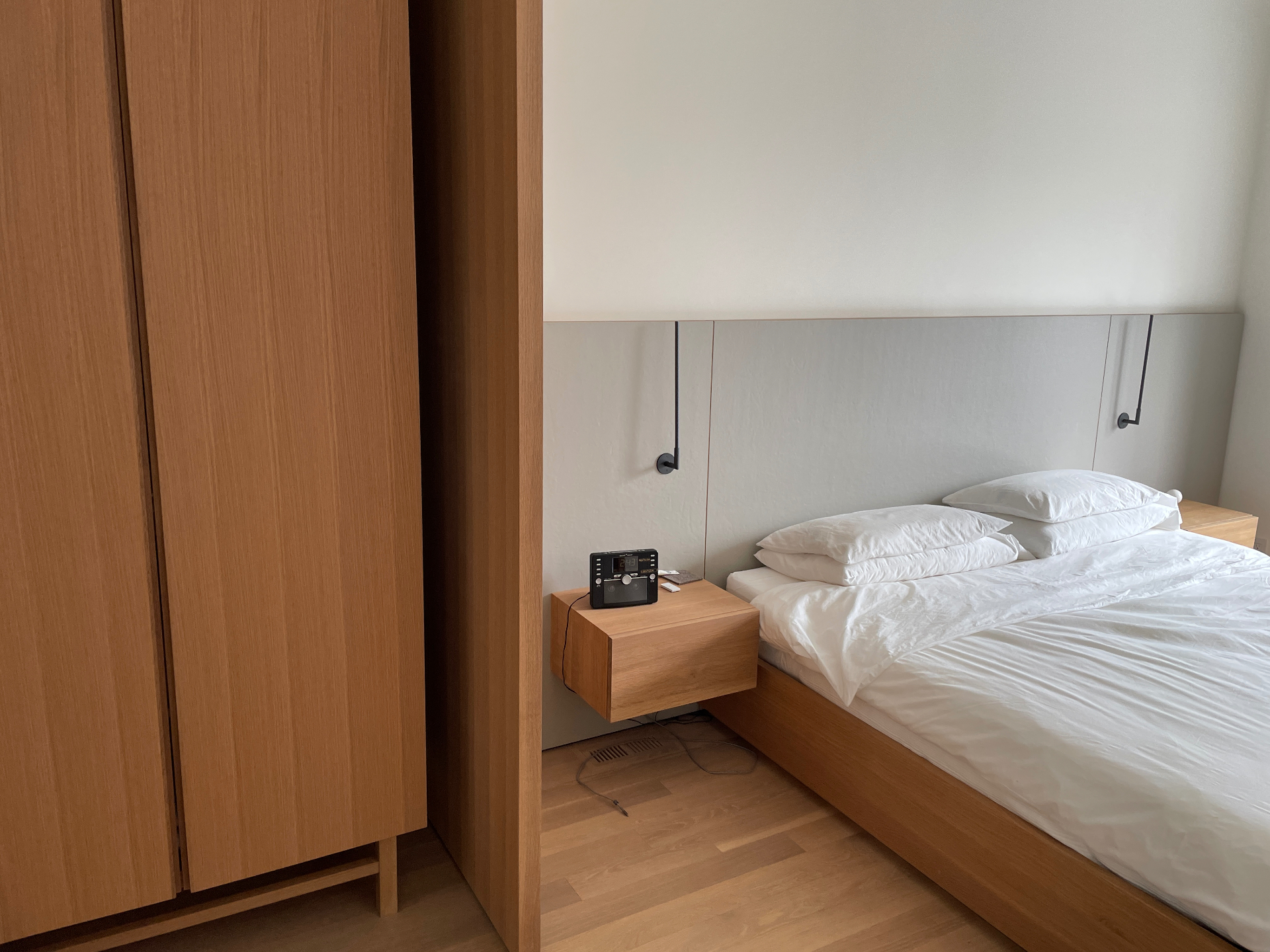 Bedroom corner showing the oak linen closet beside the bed and floating nightstand