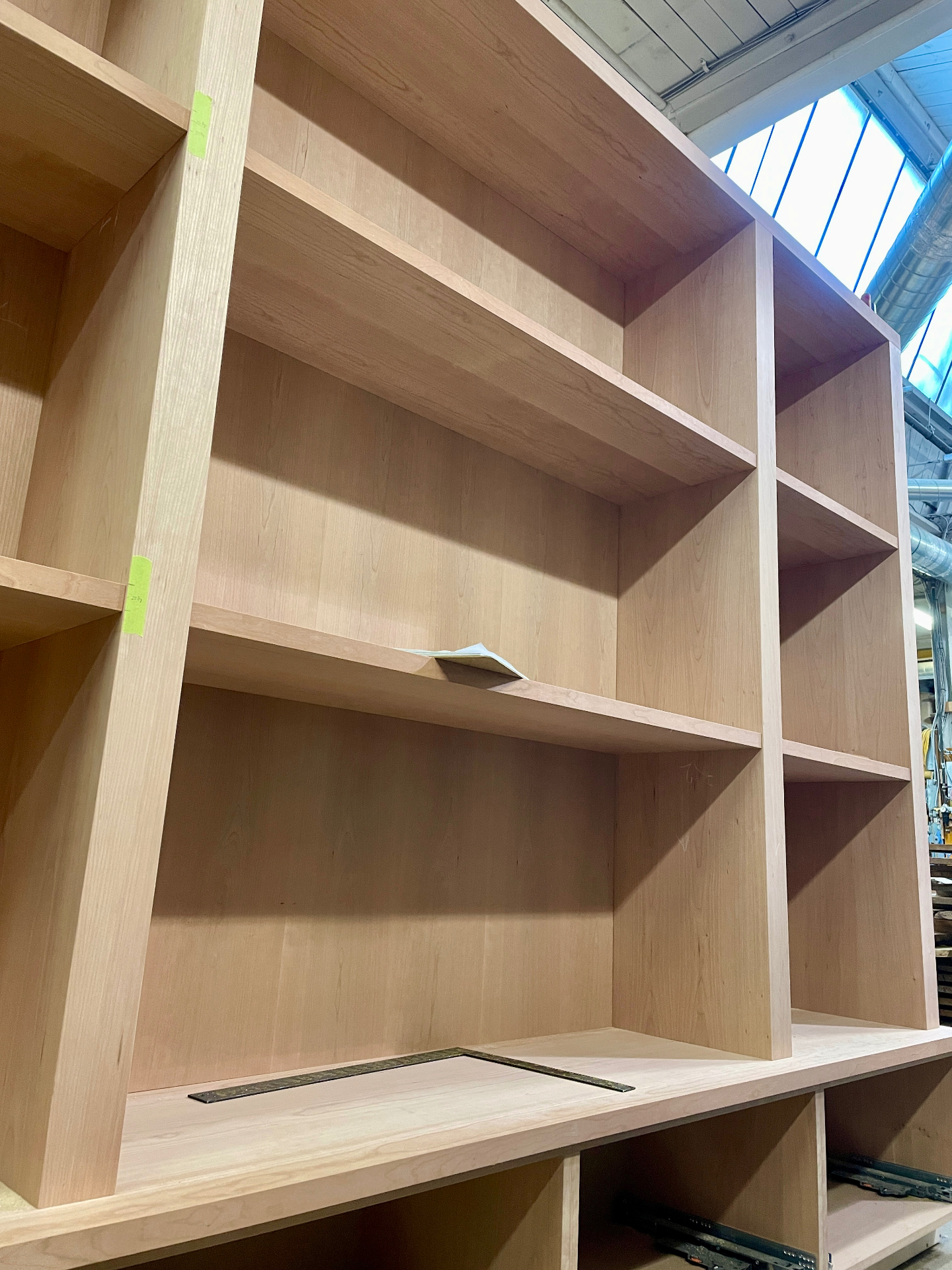 Vista em ângulo da biblioteca em folheado de cerejeira mostrando a profundidade das prateleiras e a passagem de cabos no tampo