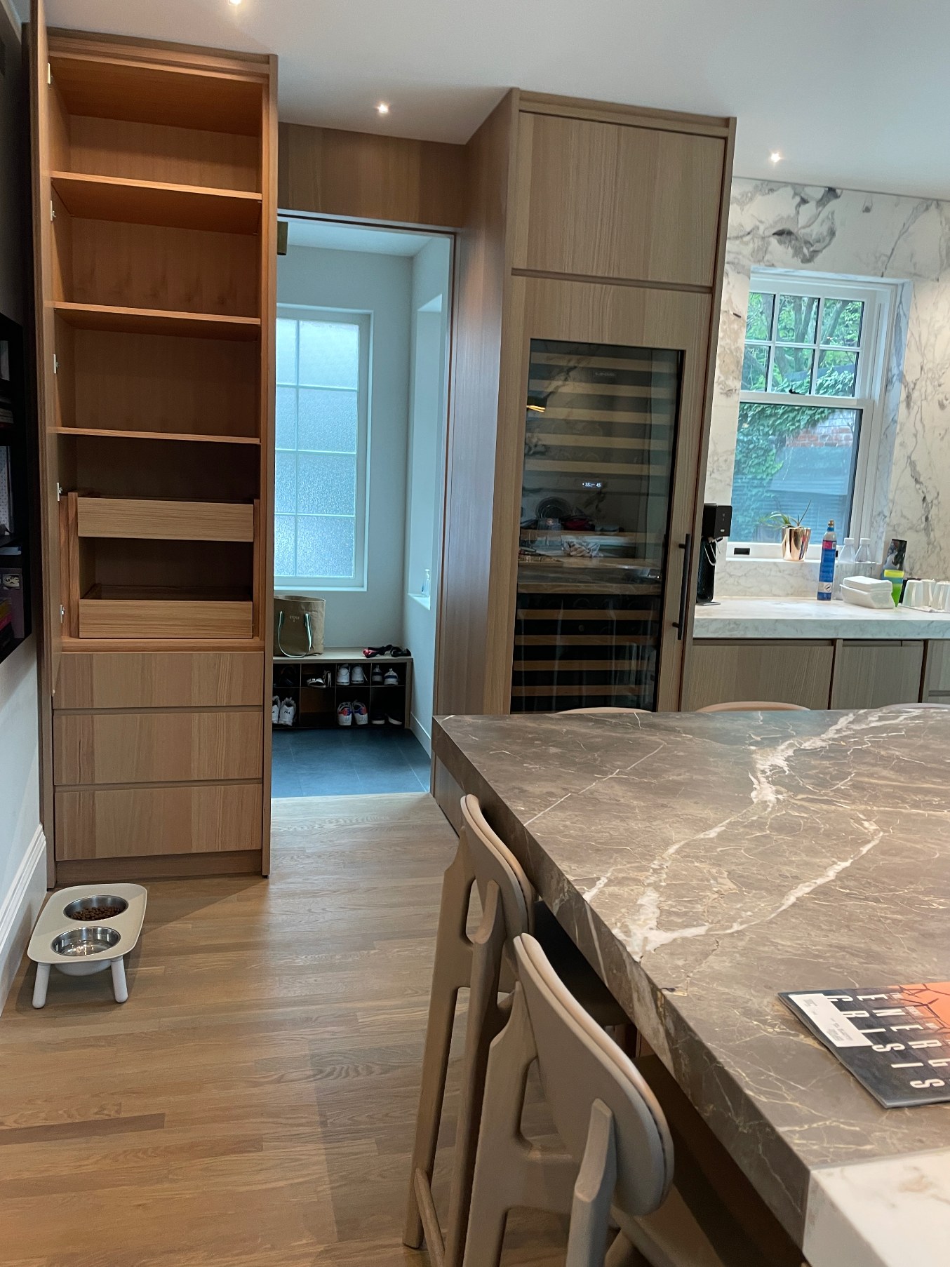 Oak pantry column and integrated wine fridge beside the marble island