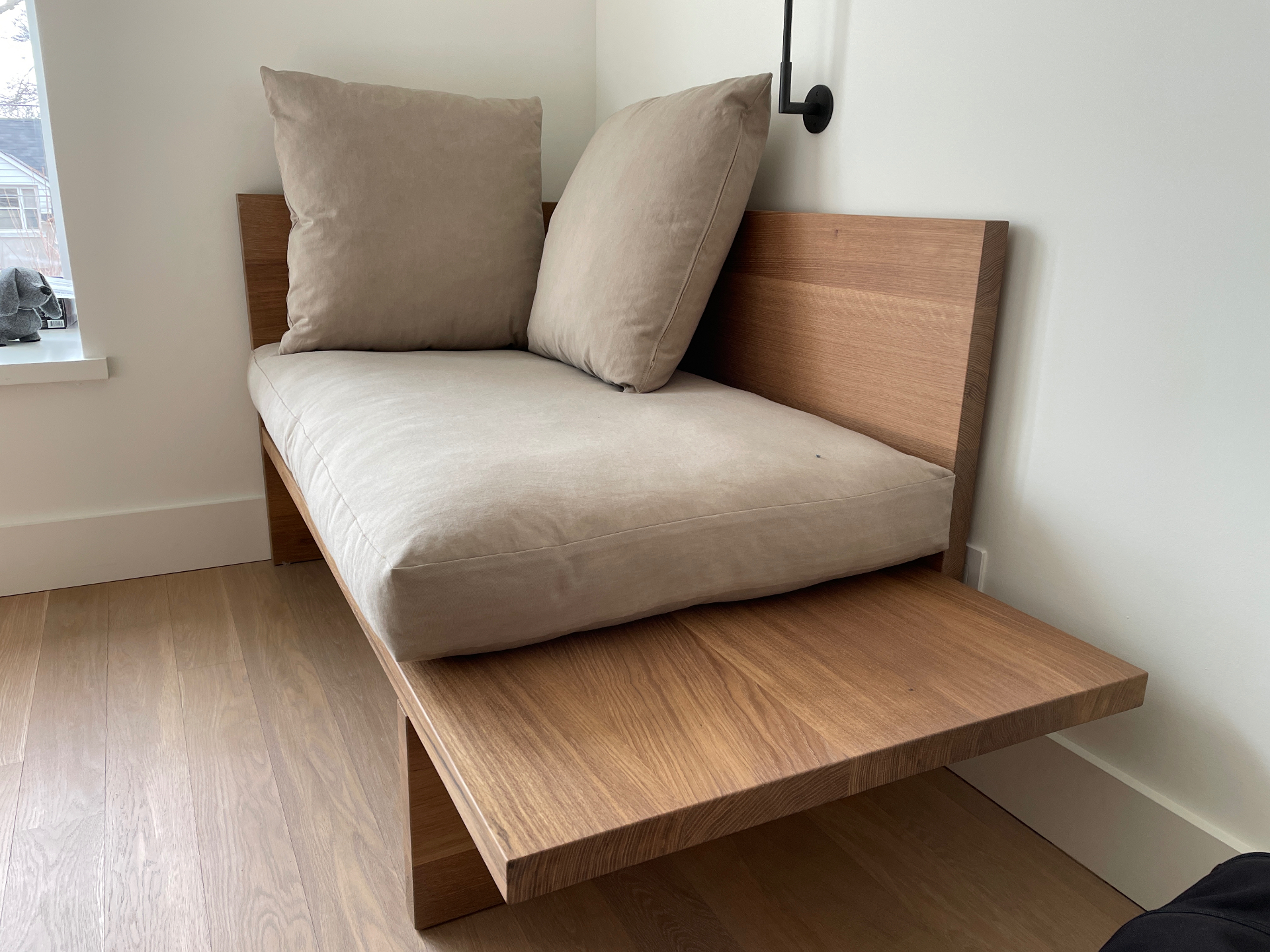 Chaise embutida em carvalho maciço com almofadas em linho no canto de um quarto