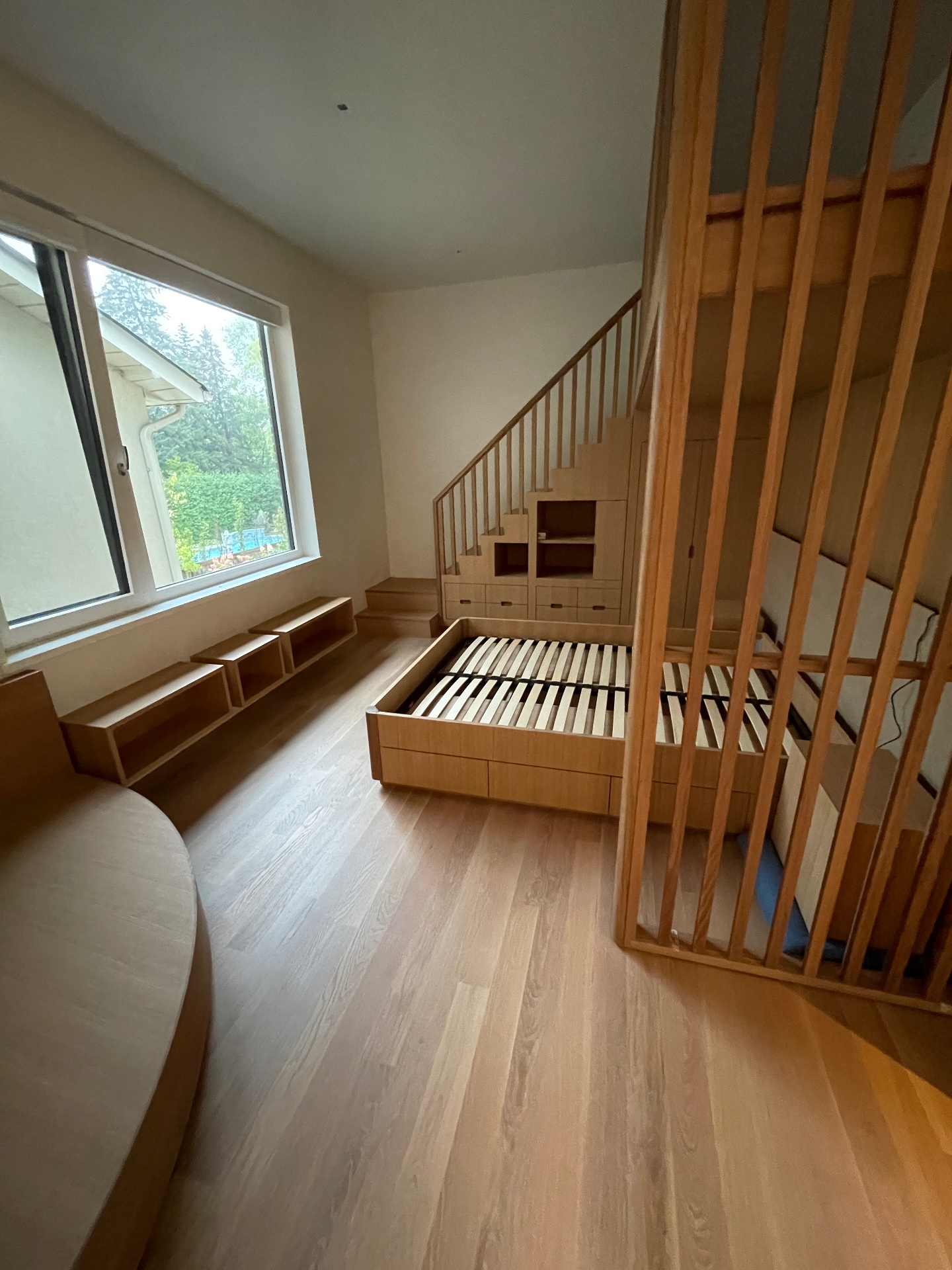 Lower oak bed with slatted base beside a large window bench
