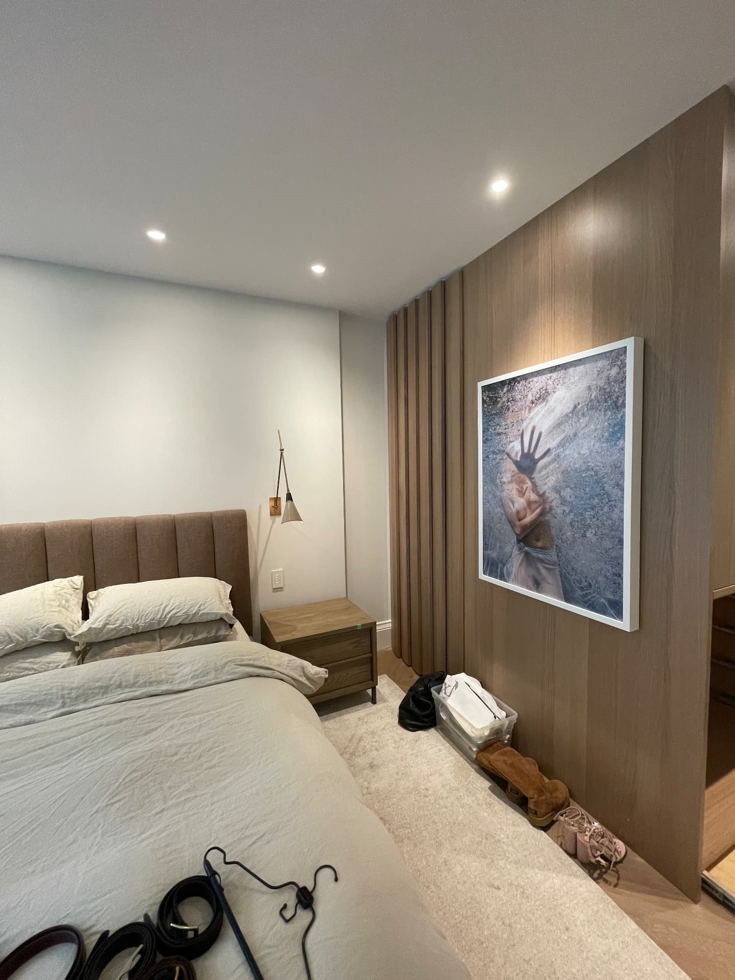 Oak panelled bedroom wall with framed artwork and integrated lighting