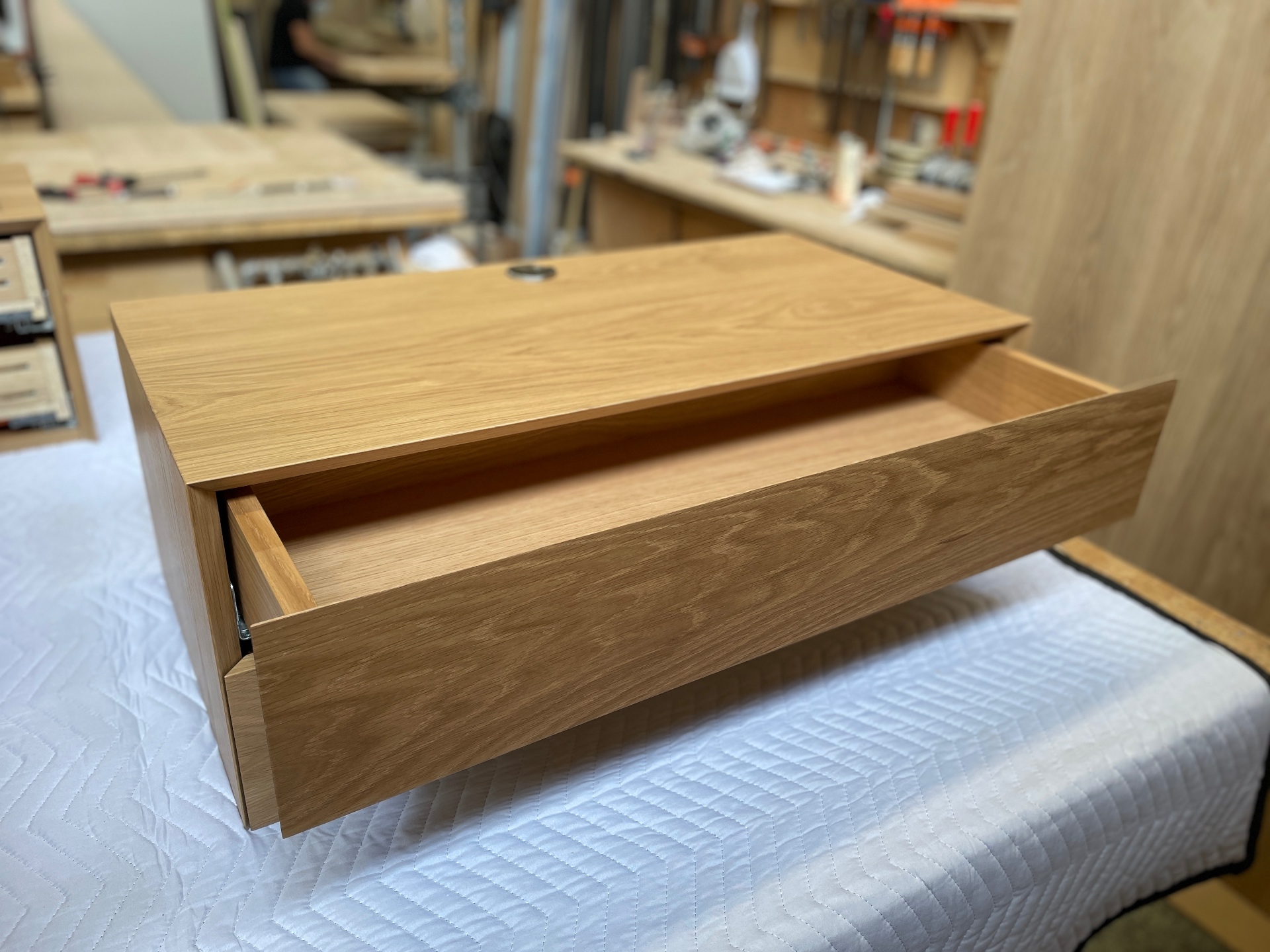 Solid oak floating nightstand with drawer open at a three-quarter angle