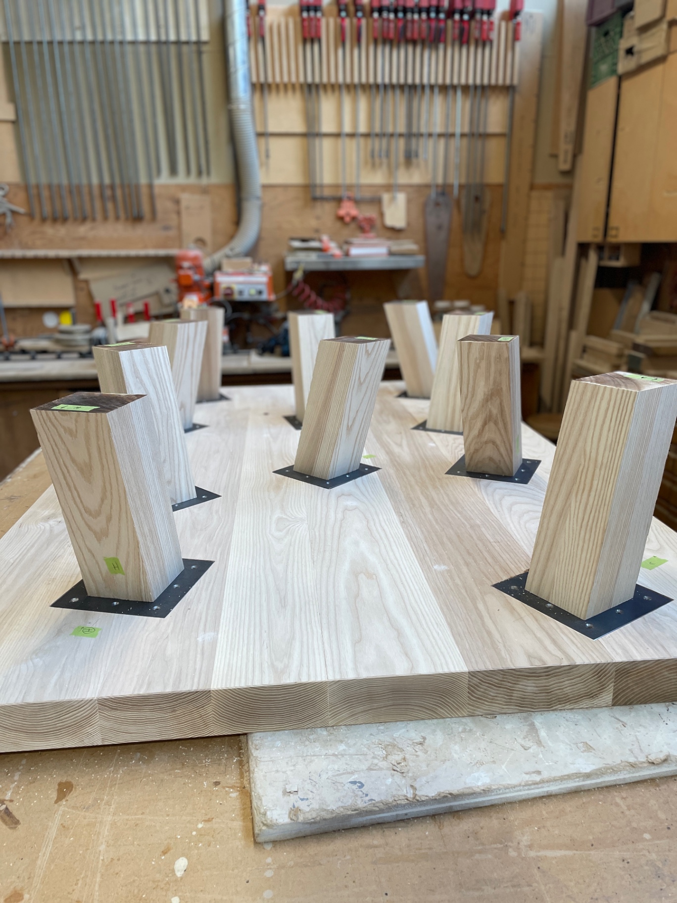 Eight tapered ash legs mounted on the underside of the slab top with steel plates