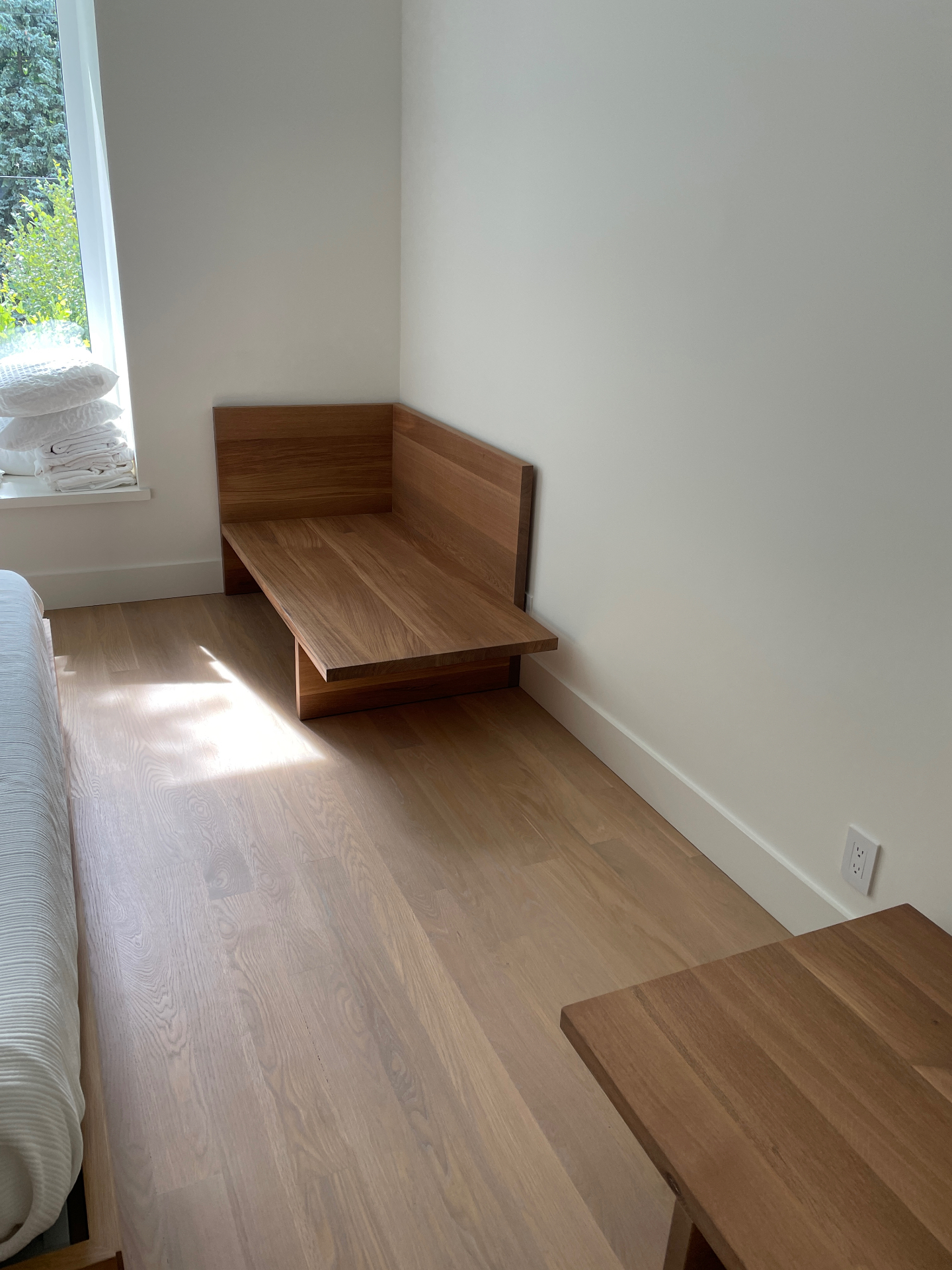 Oak chaise beside a bedroom window with morning light