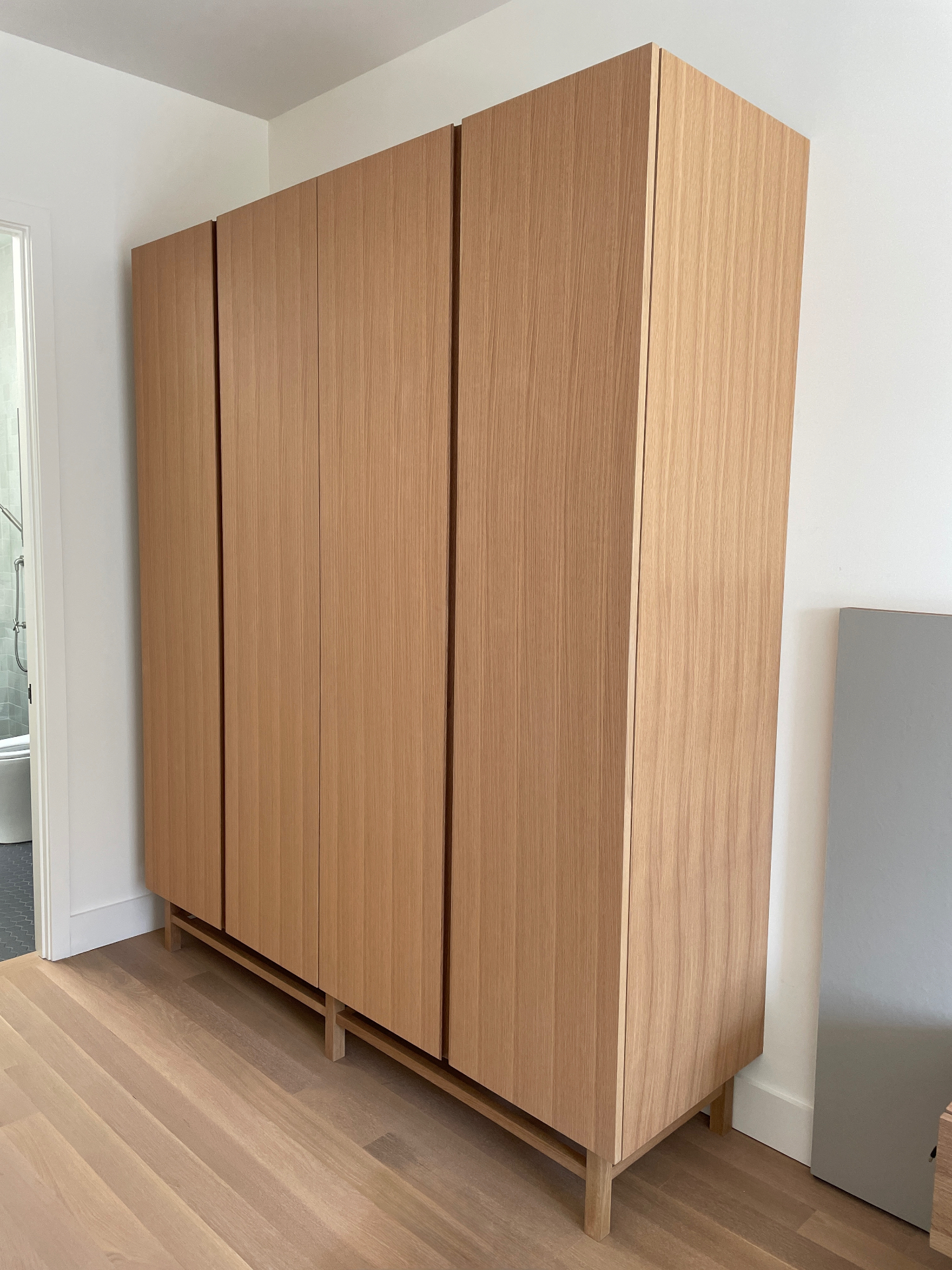 Full view of the freestanding oak linen closet on raised legs