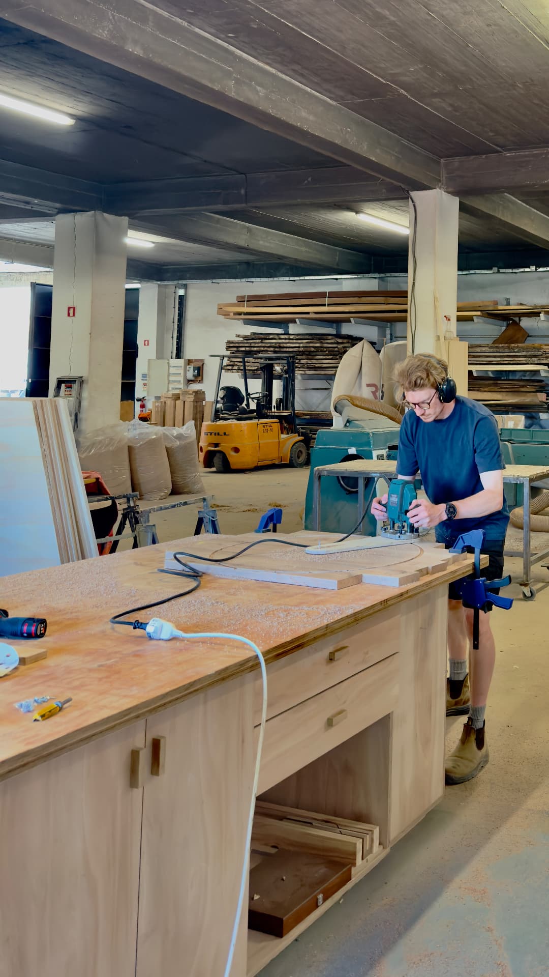 Routing a curved template on the main bench in the Lisbon workshop, timber racks behind