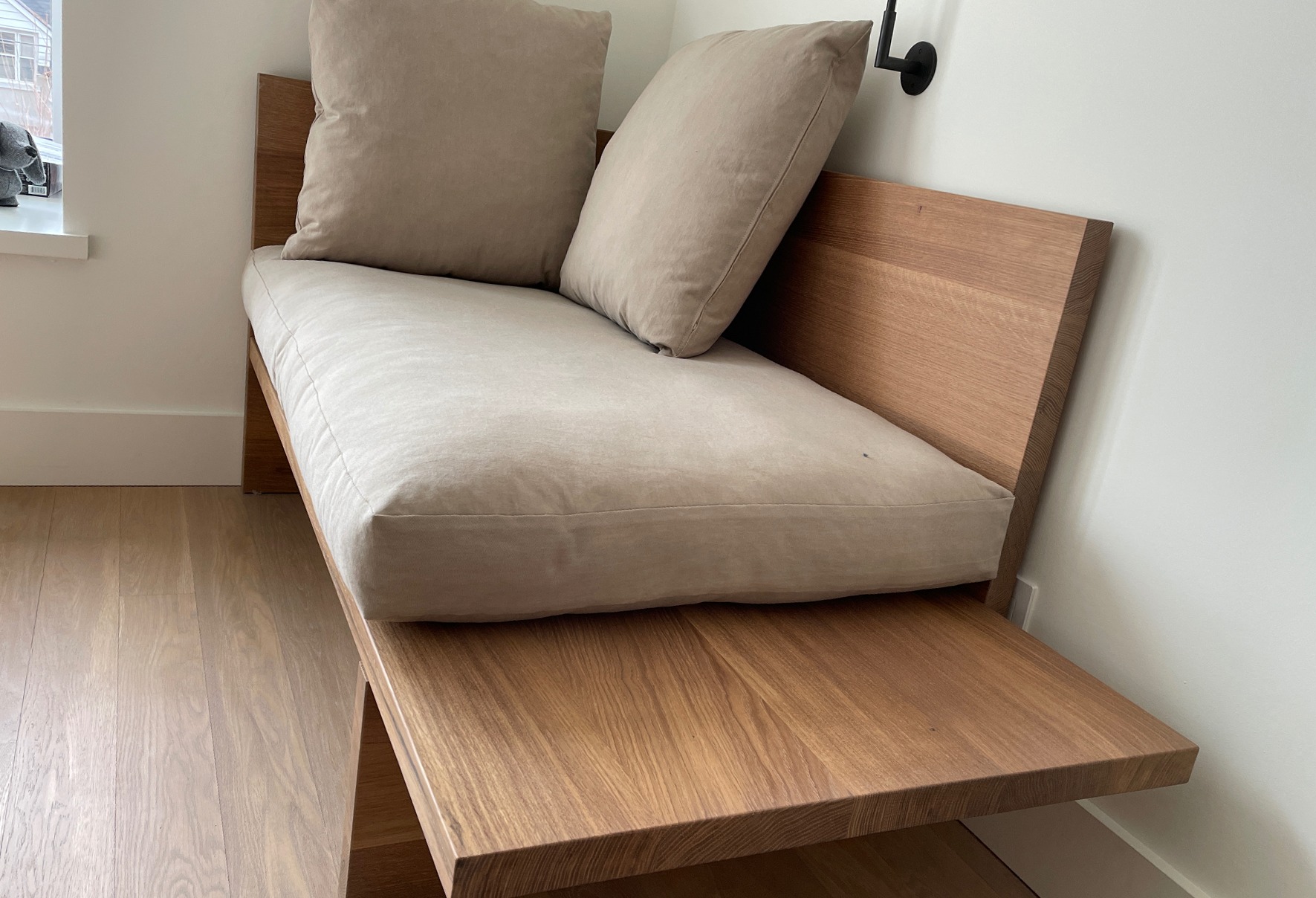 Chaise embutida em carvalho maciço com almofadas em linho no canto de um quarto